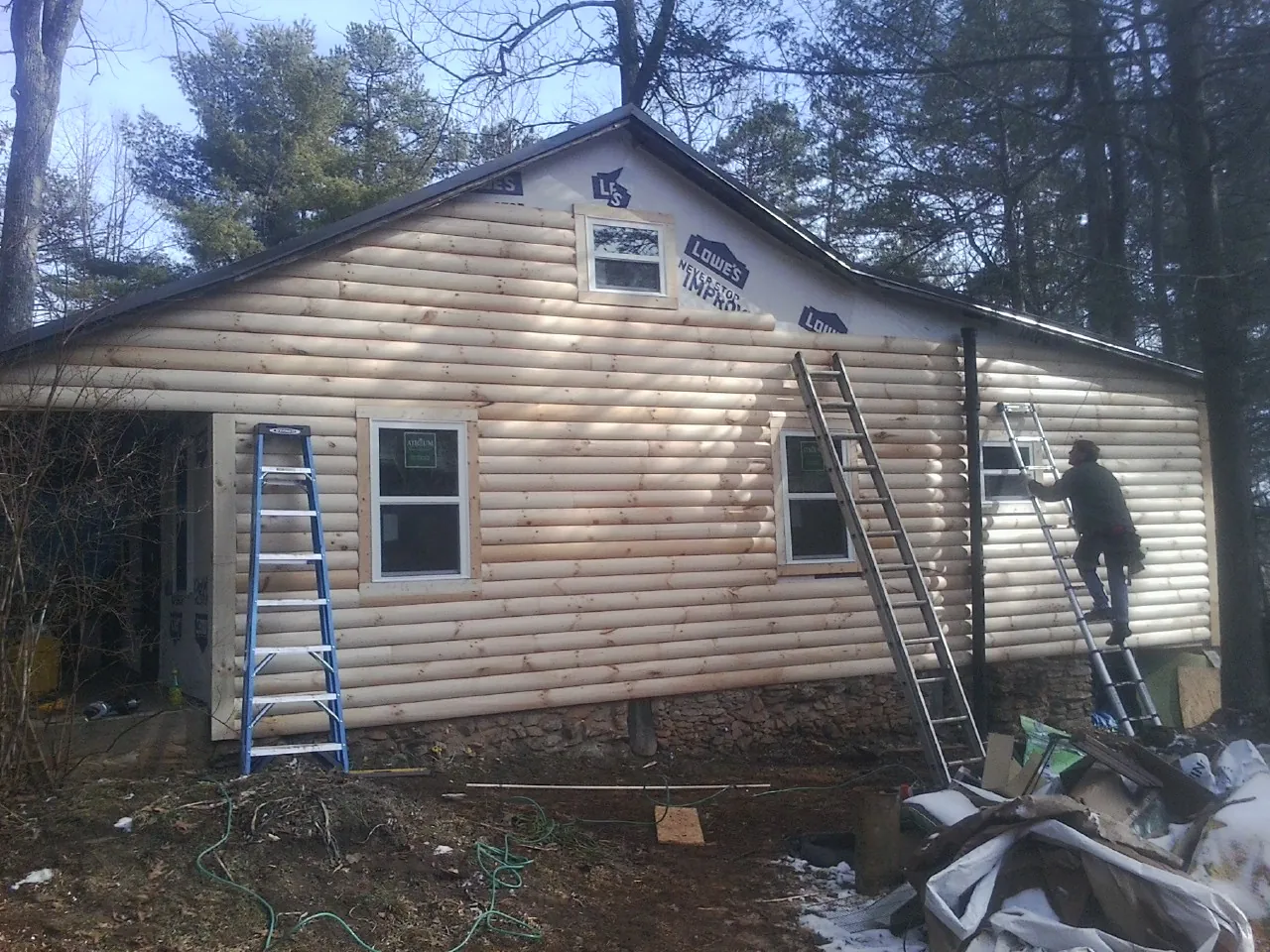 Ladders set against fresh log siding during an exterior remodel in Westport