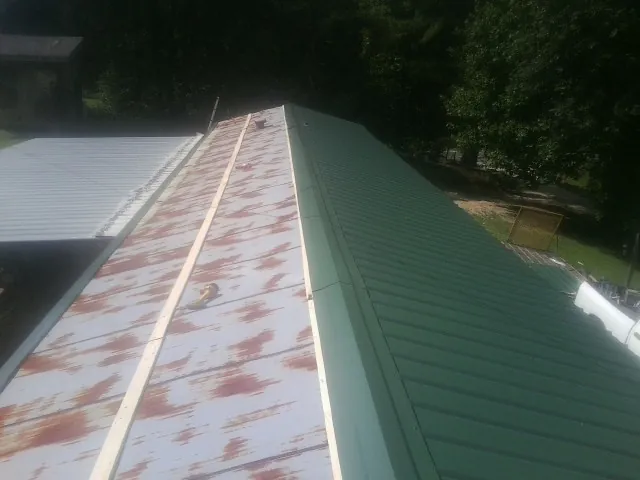 Old rusted panels beside newly installed green metal roofing — Wind Damage Roof Repair by Roofing Brothers in Westport