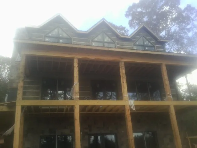 Dormers and porch framing on a large log home under construction — Roof Coating work by our crew in Westport